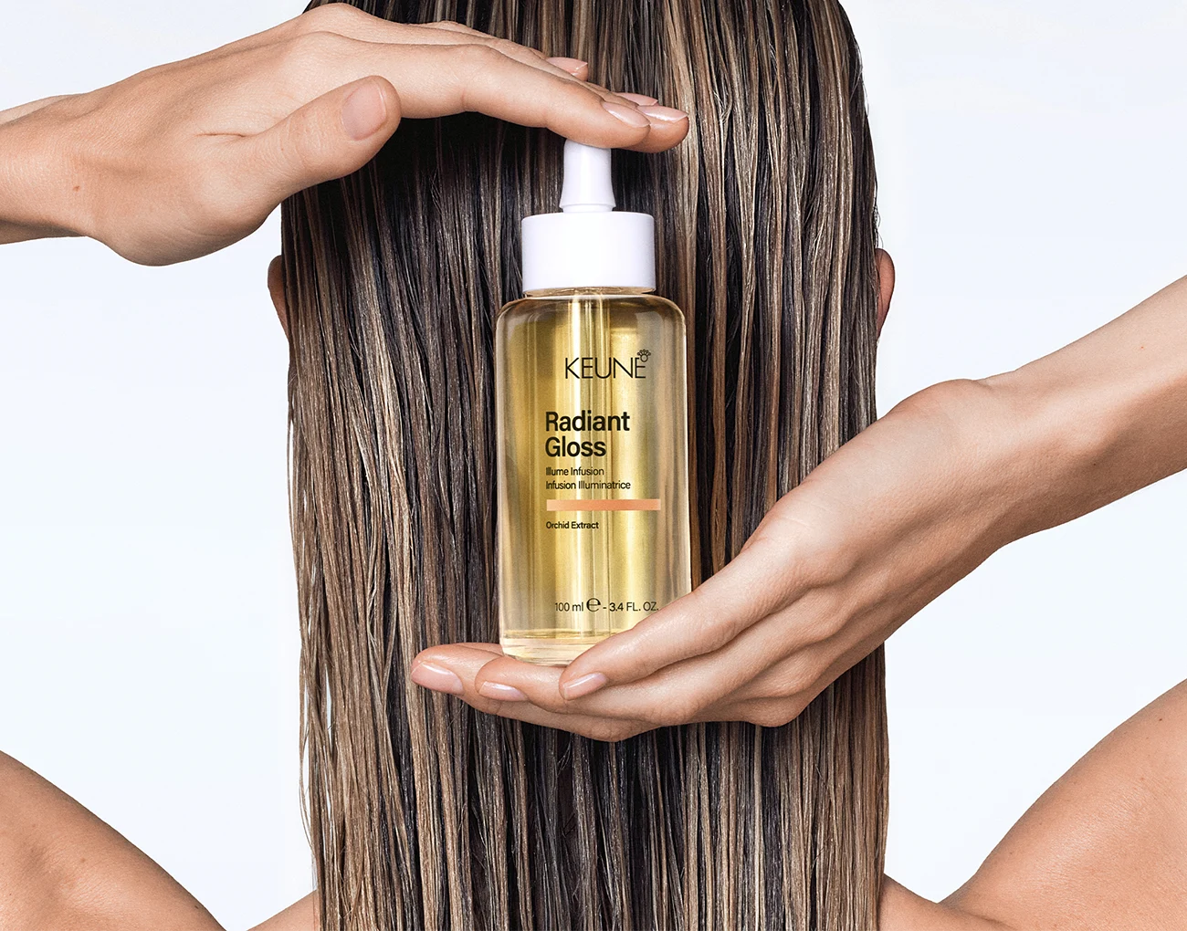 Keune Radiant Gloss Illume Infusion hair oil held against glossy highlighted hair