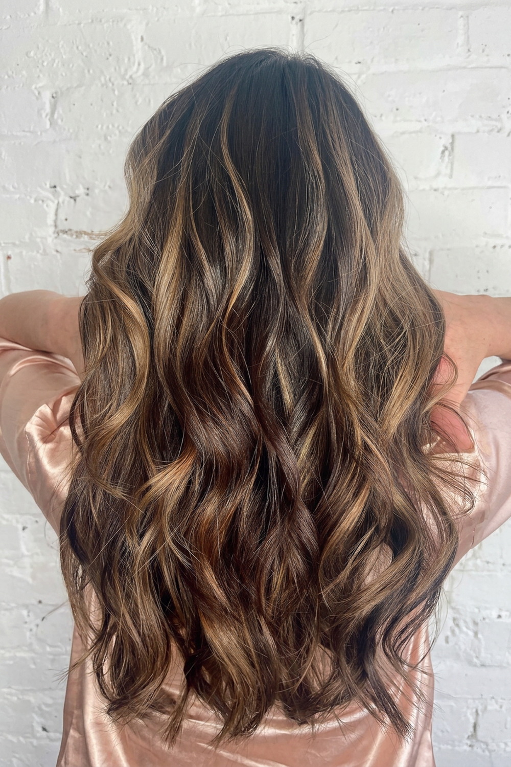 Dark brunette with caramel balayage through long waves, Utah balayage specialist.