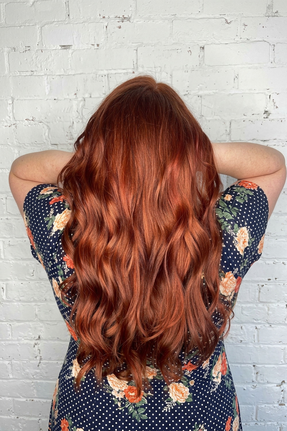 Glossy copper auburn waves on a white brick wall, red and copper hair colour in Utah.